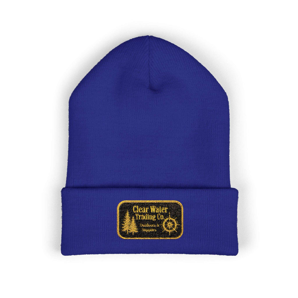A royal blue knit beanie hat with a folded cuff, featuring a rectangular embroidered patch on the front that reads 'Clear Water Trading Co' with a gold-toned design.