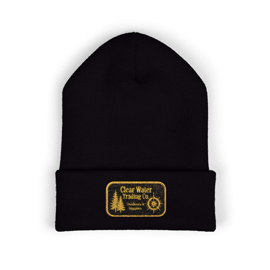 A black knit beanie hat with a folded cuff, featuring a rectangular yellow embroidered patch on the front that reads 'Clear Water Trading Co' with a tree and compass design, shown on a plain white background.