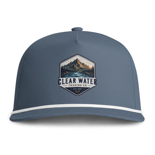 A slate blue snapback cap featuring a white stripe along the brim and a central embroidered patch with a mountain landscape and the text 'CLEAR WATER TRADING CO.'.
