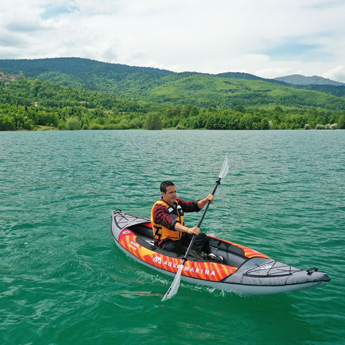 Person kayaking on a lake with mountains in the background