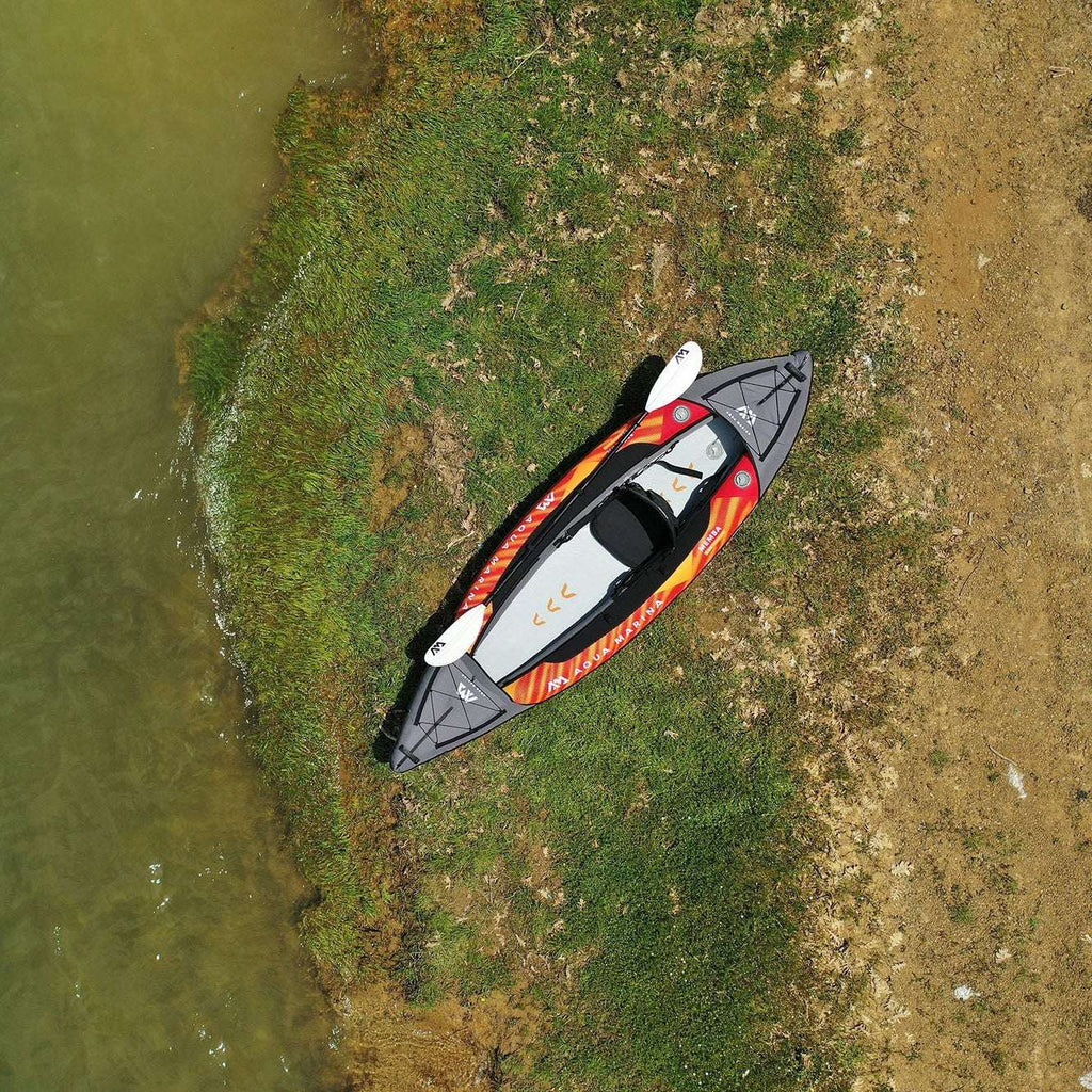Inflatable kayak on a grassy patch next to a body of water