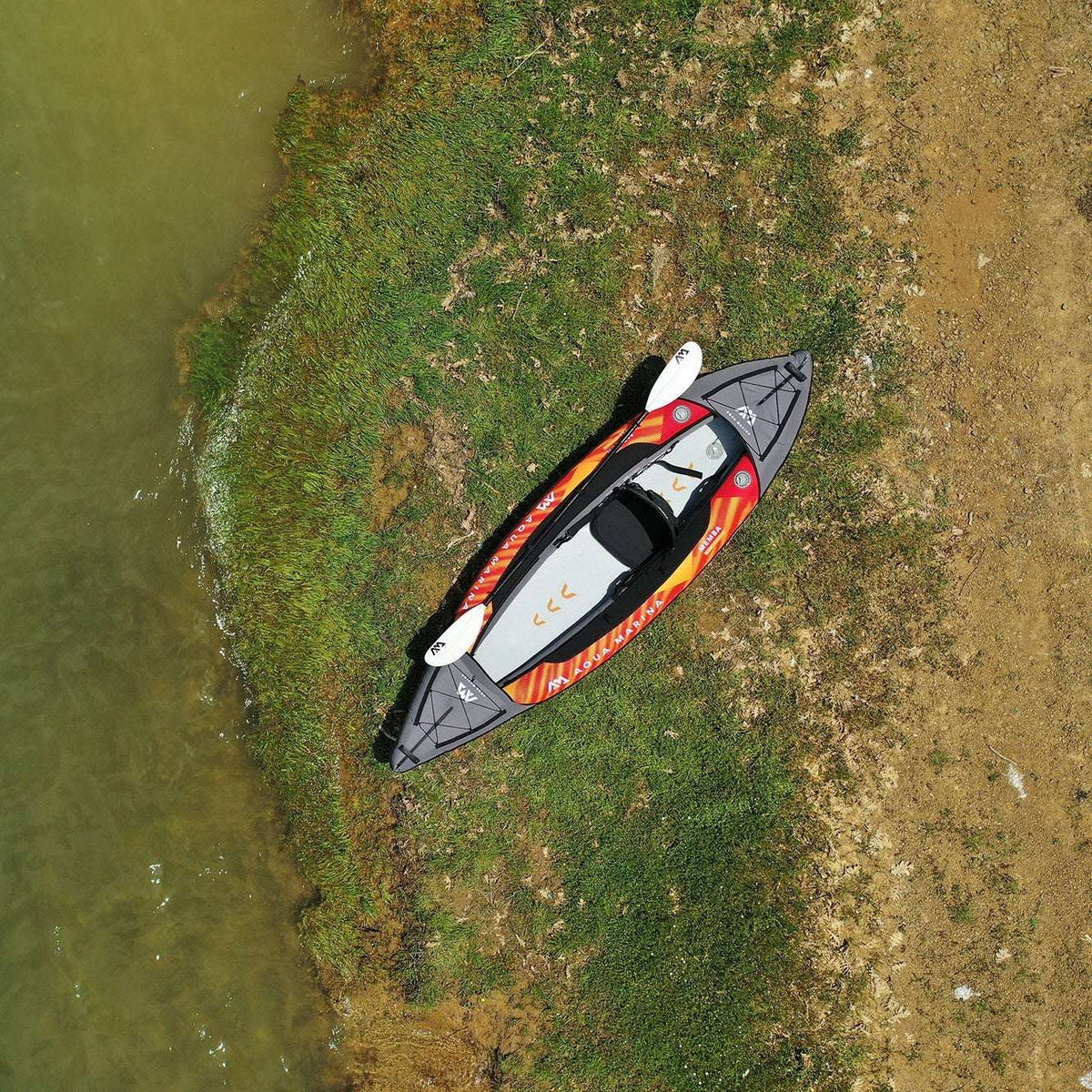 Inflatable kayak on a grassy patch next to a body of water
