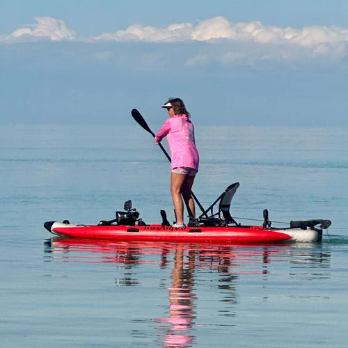 Person paddleboarding on a calm body of water with a clear sky.